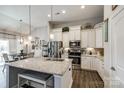 Well-lit kitchen featuring a large island, stainless steel appliances, white cabinetry, and modern pendant lighting at 1024 Mayapple Way, Belmont, NC 28012