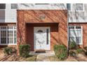 Close up of a white door with a glass insert surrounded by brick and green shrubs at 1127 Central Park Cir, Davidson, NC 28036