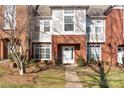 View of a townhome's exterior featuring a white door, brick facade, and manicured shrubs at 1127 Central Park Cir, Davidson, NC 28036