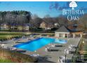 Community pool and lounge area with tables and chairs and nearby pool house at 3427 Laurel Oak Ln, Gastonia, NC 28056