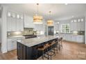 Open kitchen with large island, stainless appliances, white cabinets, and hardwood floors at 5026 Ohm Ln, Charlotte, NC 28270