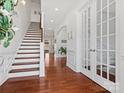 Elegant hallway showcases hardwood floors, a staircase, arched doorway, and decorative French doors at 1016 Hickory Pine Rd, Waxhaw, NC 28173