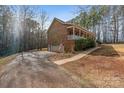 Side view of a brick house with an attached garage and long porch, nestled among tall trees at 201 Olive Rd, Stony Point, NC 28678