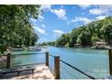 Relaxing lake view from a wooden deck with steel bar railing and dock. Blue water, blue sky, and mature trees at 353 Whippoorwill Rd, Mooresville, NC 28117