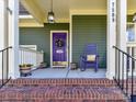 Inviting front porch featuring a purple door, rocking chair, and decorative details for a cozy feel at 7509 Thorn Creek Ln, Tega Cay, SC 29708