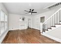 Bright living room with hardwood floors, white trim, fireplace, ceiling fan, and staircase leading to the upper level at 1101 Lancaster Ave, Monroe, NC 28112