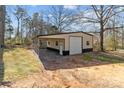 Detached garage with a covered area, featuring a roll-up door and neutral color scheme, in a wooded setting at 1216 Innis Ave, Kannapolis, NC 28081