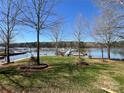 Beautiful waterfront view with mature trees, green grass, and a boat dock at 103 Dogwood Cir, New London, NC 28127