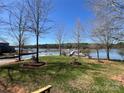 Scenic waterfront view with lush green grass, a dock, boats, and mature trees at 103 Dogwood Cir, New London, NC 28127