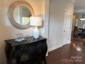 Elegant entryway featuring a decorative chest, round mirror, stylish lamp, and hardwood floors leading into the home at 1220 Avalon Pl, Matthews, NC 28104