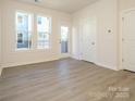 The bedroom with wood-look flooring, large windows, and a white door leads to a balcony at 1307 Cerium Way, Charlotte, NC 28211