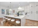 Bright kitchen featuring a large waterfall island with seating, modern appliances, and pendant lighting at 144 Sardis Ln, Charlotte, NC 28270