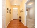 Bright foyer featuring hardwood floors, warm-colored walls, decorative lighting, and an open doorway to another room at 4642 Willow Glen Rd, Harrisburg, NC 28075