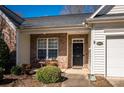 Inviting front porch featuring brick accents, a black front door with a gold number plate, and neat landscaping at 4642 Willow Glen Rd, Harrisburg, NC 28075