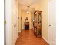 Hallway with wood floors, light yellow walls, multiple doors, decorative cabinet, a desk, and elegant lighting at 4642 Willow Glen Rd, Harrisburg, NC 28075