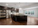 Modern kitchen featuring dark cabinetry, stainless steel appliances, and a large island with granite countertops at 6112 Canyon Trl, Denver, NC 28037