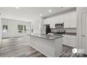The kitchen with island features granite countertops and stainless steel appliances, and opens to the living area at 1211 Pine St # A, Mooresville, NC 28115