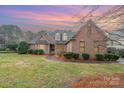 Beautiful brick home featuring manicured landscaping and a well-maintained lawn at sunset at 5125 Belicourt Dr, Charlotte, NC 28277