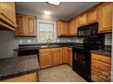 Well-lit kitchen showcases oak cabinets, black appliances, granite countertops, and durable tile flooring at 580 Earley St, Kannapolis, NC 28083
