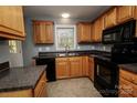 Functional kitchen design features oak cabinets, black appliances, granite countertops, and tile flooring at 580 Earley St, Kannapolis, NC 28083
