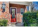 Inviting red front door with glass panels, flanked by lush greenery and a brick facade at 615 Bourton House Dr, Charlotte, NC 28211