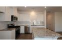 Bright kitchen features white cabinets, stainless appliances, and a granite island at 795 Earhart Nw St, Concord, NC 28027