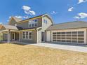 Back exterior view showcasing covered patio, grassy yard and attached garage at 1010 Rolling Meadows Dr # Rm14, Mooresville, NC 28115