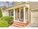 Inviting front porch with white columns, decorative lighting, brick steps and manicured green bushes at 6458 Chadwell Ct # 30, Indian Land, SC 29707