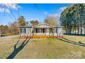 Inviting single-story home featuring a wooden porch, gray siding, and manicured front lawn at 8670 Carroll St, Hickory, NC 28601
