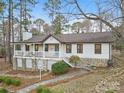 Beautiful home showcasing a covered porch and a stone foundation, nestled among mature trees at 10031 Bora Bora Dr, Tega Cay, SC 29708