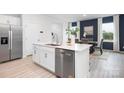 Modern kitchen features white cabinetry, stainless steel appliances, and an island with a sink and dishwasher at 11205 Cardinal Creek Ave, Charlotte, NC 28215