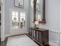 Bright foyer features a decorative mirror, area rug, and stylish cabinet with double doors leading to the outside at 13114 Long Common Pkwy, Huntersville, NC 28078