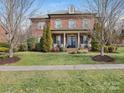 Beautiful two-story brick home with a manicured lawn and inviting front porch with classic architectural details at 13114 Long Common Pkwy, Huntersville, NC 28078