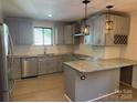 Modern gray kitchen featuring granite countertops, stainless steel appliances, and stylish pendant lighting at 3332 Draper Ave, Charlotte, NC 28205
