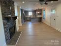 Spacious open-concept living room with a stone fireplace, hardwood floors, and adjacent modern kitchen at 3332 Draper Ave, Charlotte, NC 28205