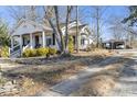 A quaint white house with a covered porch and a carport in the back, surrounded by lush greenery at 940 N New Hope Rd, Gastonia, NC 28054