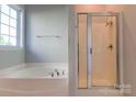 Bathroom with a separate tub and shower enclosed by a glass sliding door at 10546 Tintinhull Dr, Indian Land, SC 29707