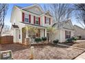 Inviting two-story home featuring a cozy front porch, red shutters, and manicured landscaping at 13206 Meadowmere Rd, Huntersville, NC 28078