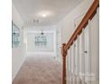 Inviting hallway featuring a wooden staircase and carpet flooring leading to a bright living area at 1386 Walnut Hill Dr, Rock Hill, SC 29732
