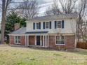 Charming two-story home with a brick facade, black door, and a welcoming covered porch at 5923 Rexwood Pl, Charlotte, NC 28210