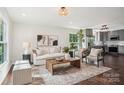 Sunlit living room featuring stylish decor, with gray trim, and open access to the modern kitchen at 6813 Elm Forest Dr, Charlotte, NC 28212
