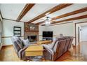 Cozy living room with exposed beam ceilings, brick fireplace, and leather seating at 7921 Altacrest Dr, Concord, NC 28027