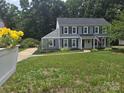 Beautiful home featuring gray siding, black shutters, a spacious front yard, and lovely landscaping at 1133 Bloom Wood Ln, Matthews, NC 28105