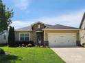 Charming one story home featuring a manicured lawn and a two car garage with a stone entryway at 305 Hemlock Bluff Ct, Denver, NC 28037
