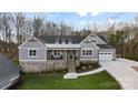 Charming front exterior features a brick base, cozy porch, and walkway to a three car garage at 324 Patternote Rd, Mooresville, NC 28117