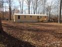 View of the mobile home exterior featuring a well-lit view and a wooden deck amidst a wooded landscape at 335 Lake Landing Dr, Salisbury, NC 28146