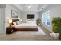 Spacious main bedroom featuring a tray ceiling, large window, and modern furniture at 5084 Parkview Way, Matthews, NC 28104