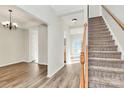 Bright entryway featuring wood flooring, a staircase, and natural light streaming through the doorway at 5323 Dewmorn Pl, Charlotte, NC 28269