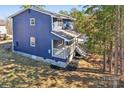 Side angle of a two-story home with a covered porch, showcasing the blue siding and landscaped yard at 14325 Rocky River E Rd, Davidson, NC 28036