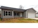 Inviting home features gray vinyl siding, a covered front porch, and a convenient attached one-car garage at 203 S Hill Ave # 3, Albemarle, NC 28001